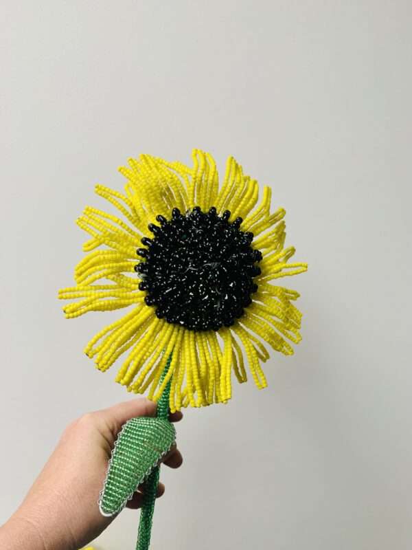 zonnebloem met zwart hart van draad en kralen in de hand