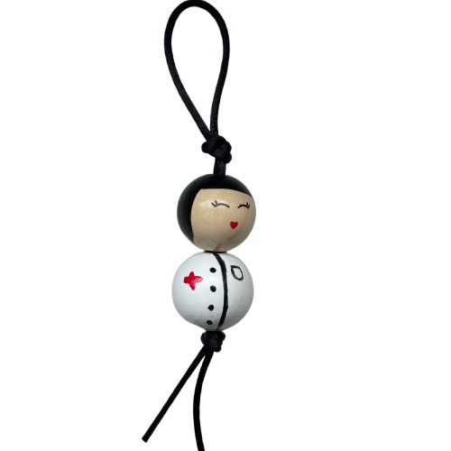 Houten zuster gelukspoppetje met zwart hoofdje en handbeschilderd zusterjasje, symbool van zorg en geluk.