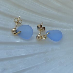 blauwe zeeglas oorbellen liggend op schelp