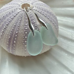 aqua zeeglas oorbellen met zilveren oorhaakjes hangend aan zeeegelschelp