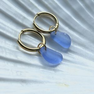 blauwe zeeglas oorbellen liggend op schelp