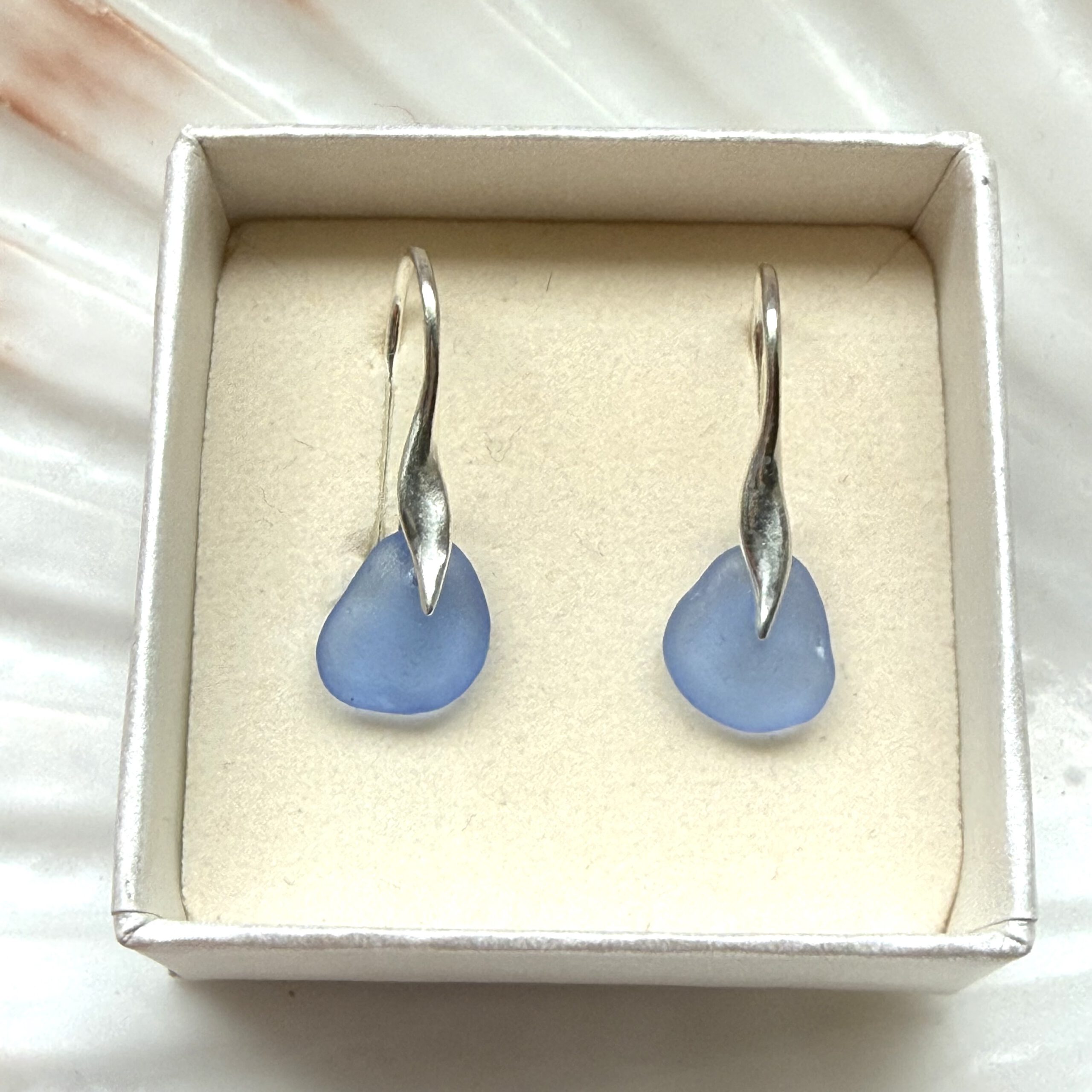 zeeglas oorbellen blauw in een sieradendoosje