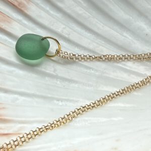 zeeglas bosgroen goud ketting liggend op een schelp